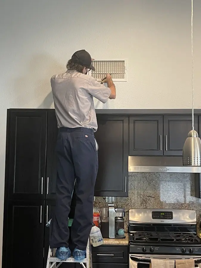 Technician inspecting an air vent during HVAC service in Franklin